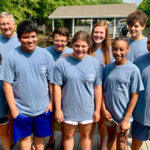 group of 9 youth and chaperones standing on a pier in matching t-shirts