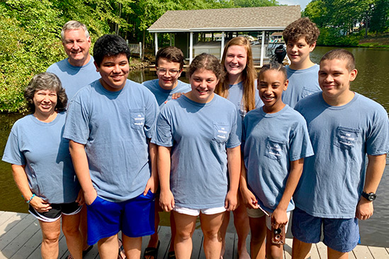 group of 9 youth and chaperones standing on a pier in matching t-shirts